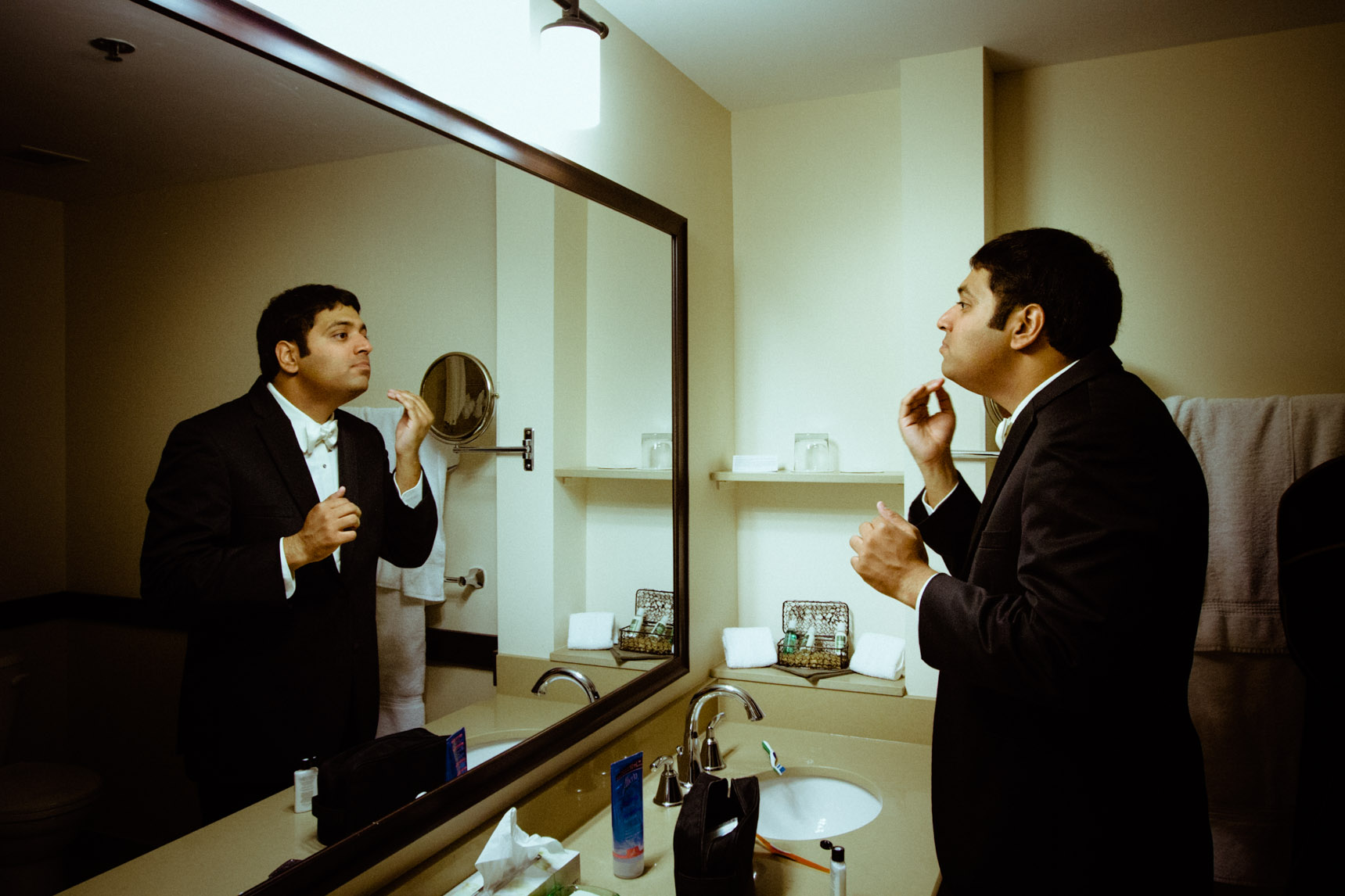 Groom prepares himself in the bathroom of hotel room.