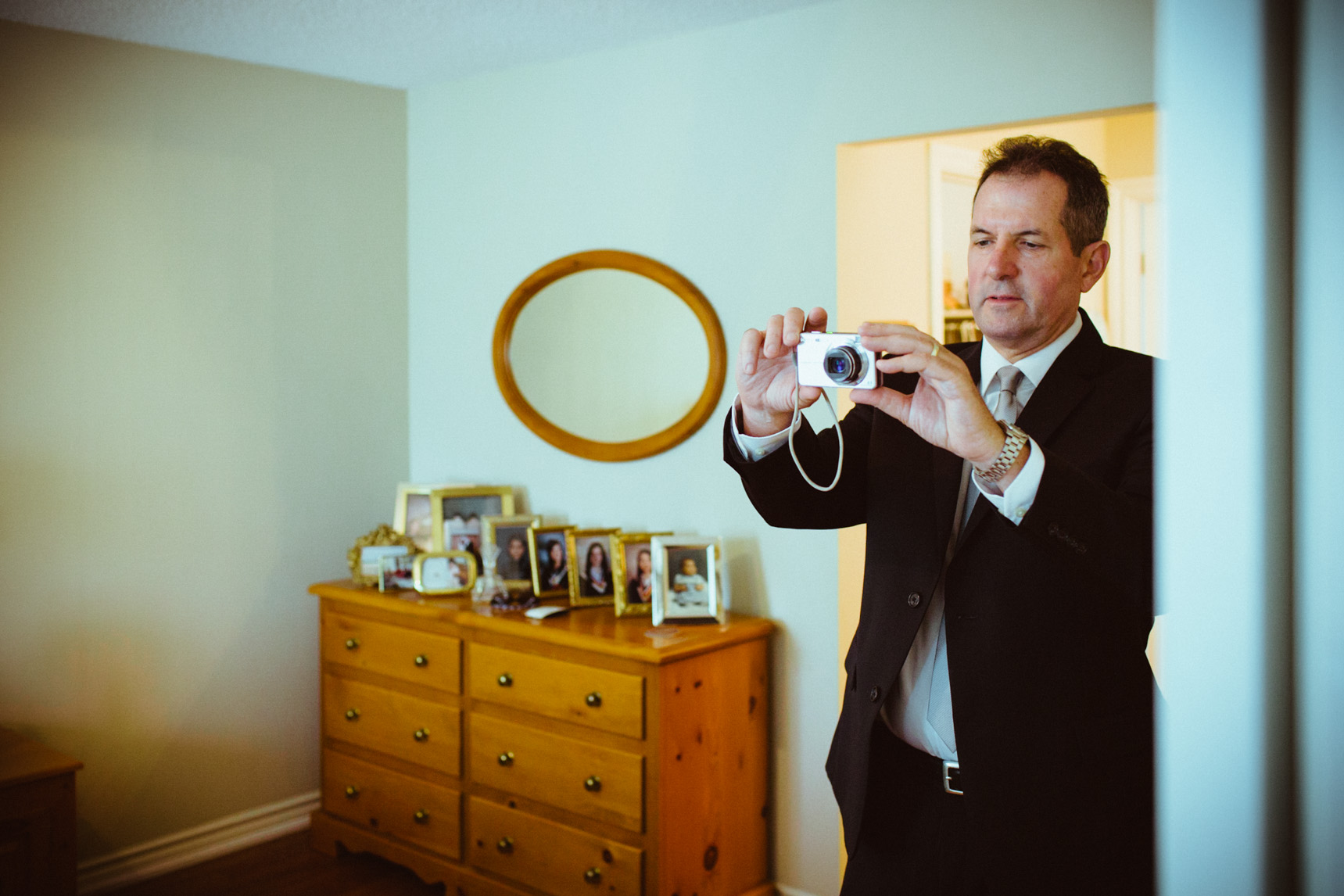 Bride's father takes a photo of the bride.