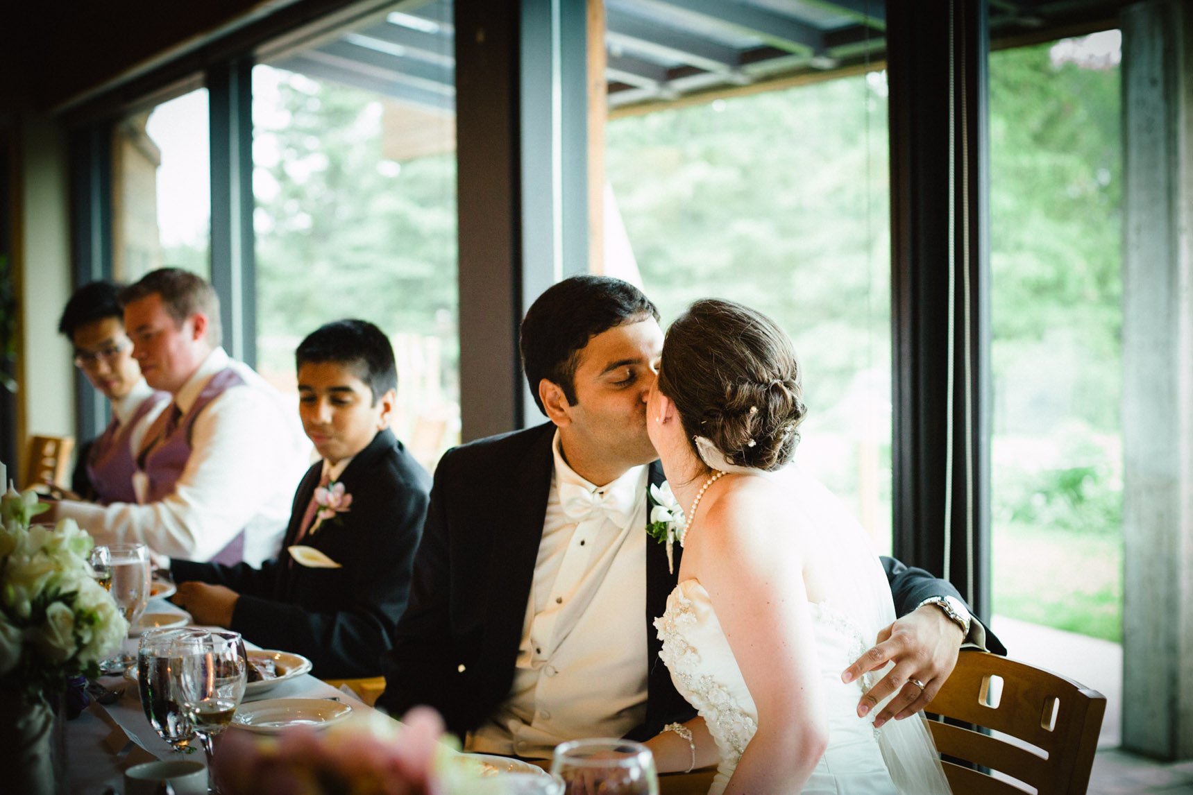 Bride and groom kissing during dinner reception after speech.