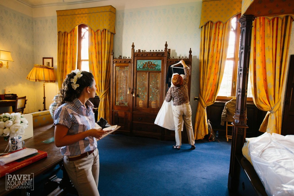 Intimate wedding photography: bride's mother hangs the dress