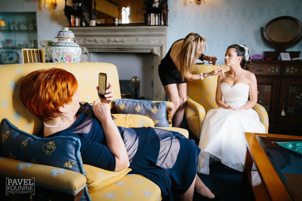 Intimate wedding photography: mother of bride captures cellphone photo of bride with makeup artist