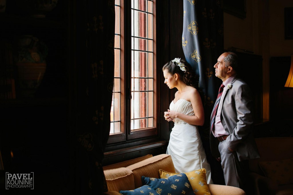 Intimate wedding photography: bride and father looking out castle window