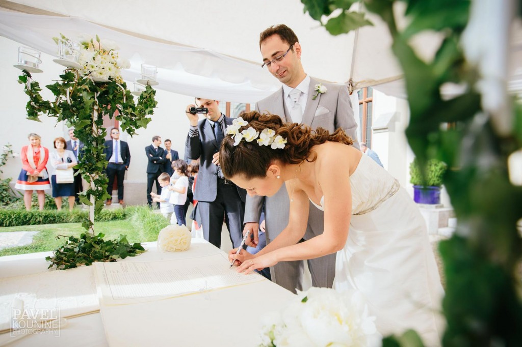 Intimate wedding photography: bride and groom sign wedding documents