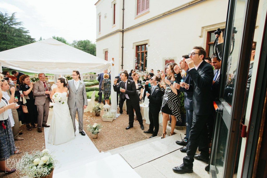 Intimate wedding photography: guests blow bubbles at bride and groom