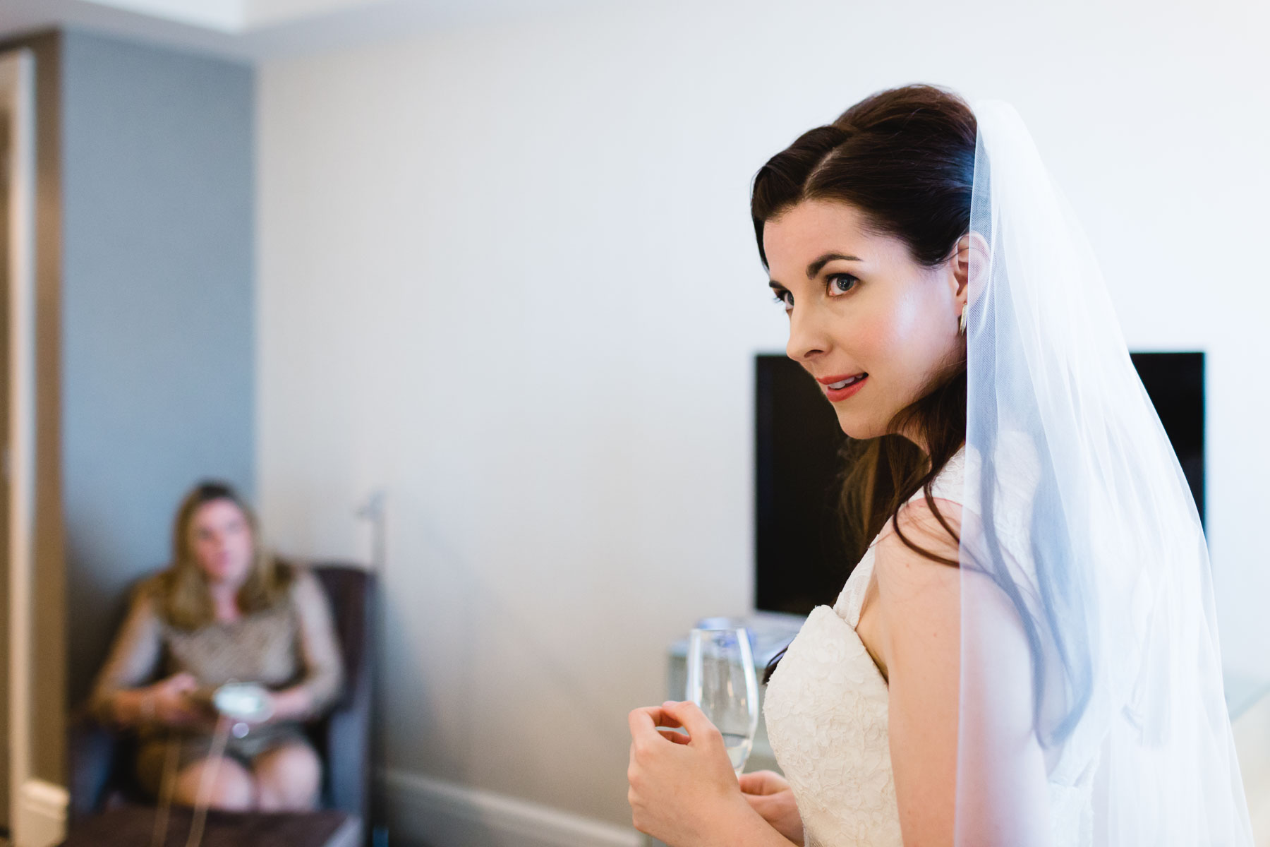 The bride looks left while holding a flute of sparkling wine in this photo from the Trump Hotel.