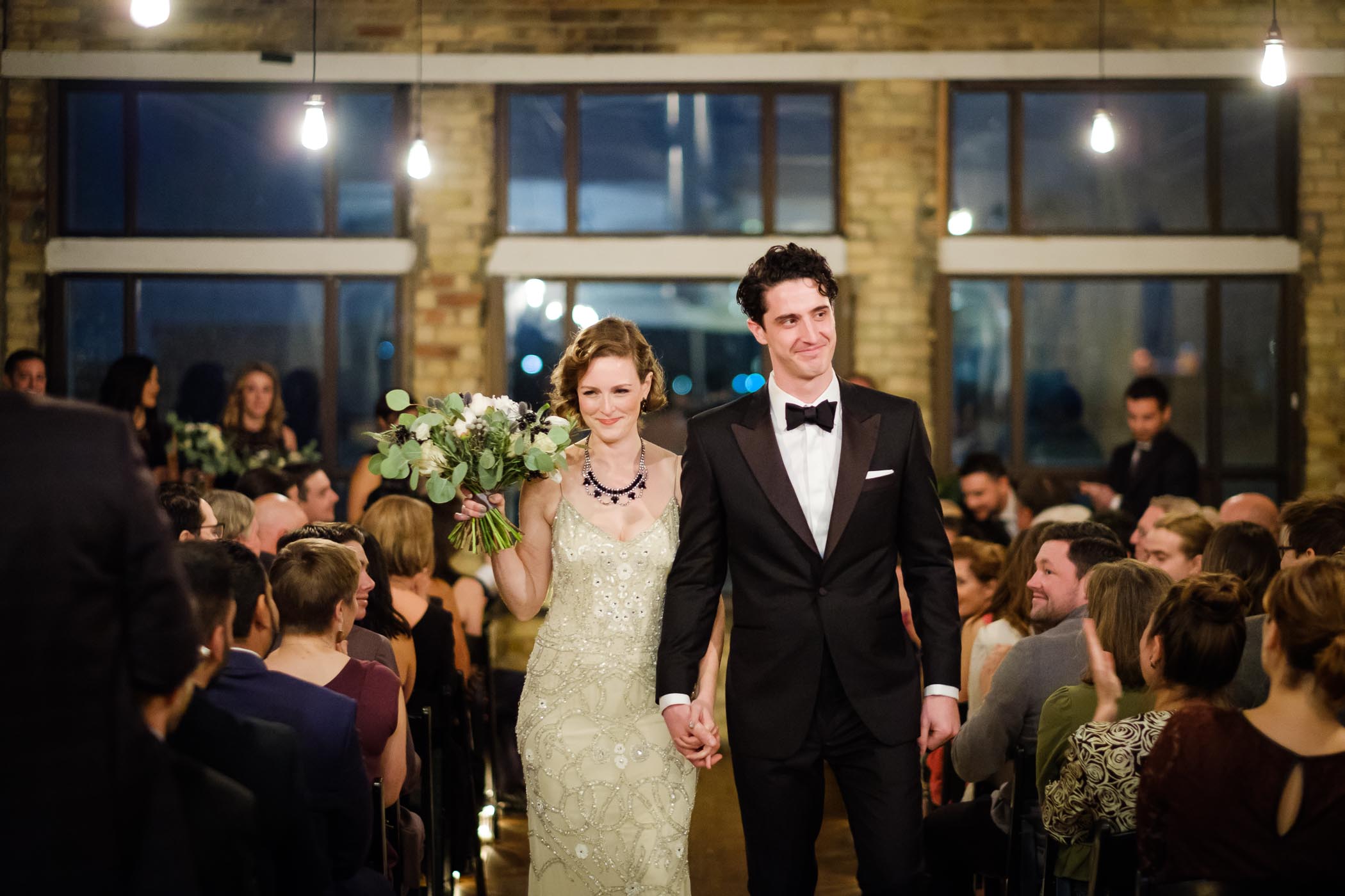 After getting married, the bride and groom walk down aisle at The Burroughes Building.