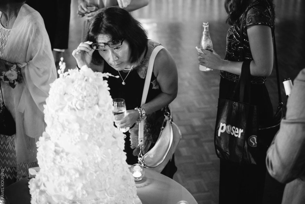Photojournalistic wedding photography cocktail hour, a woman examines the wedding cake at Boulevard Club wedding