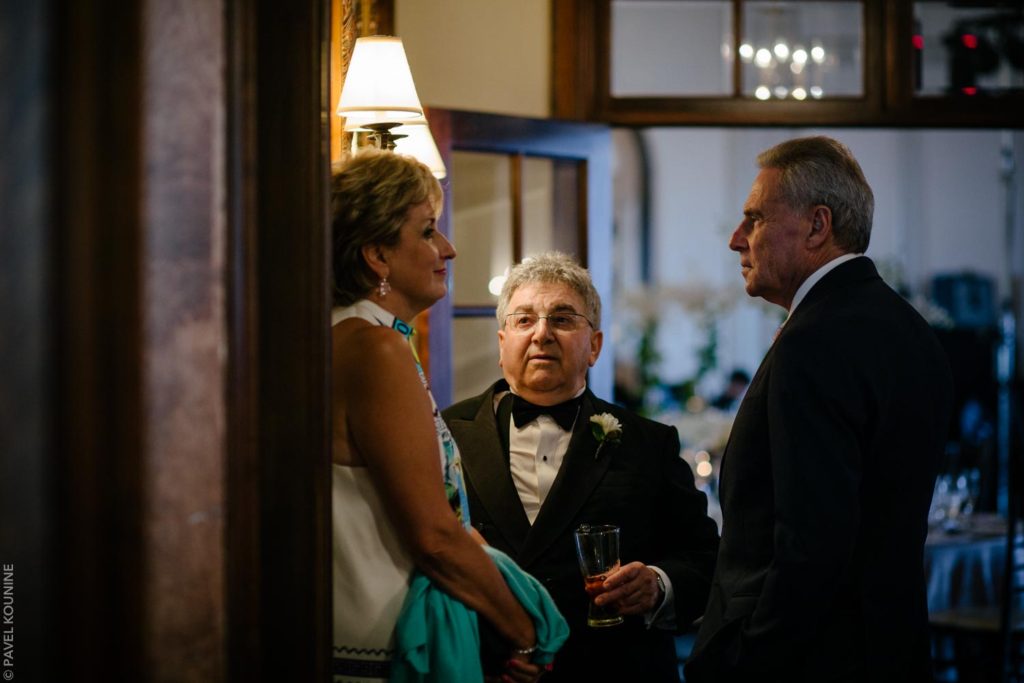 Three guests talking under dramatic lighting at Boulevard Club wedding in Toronto.