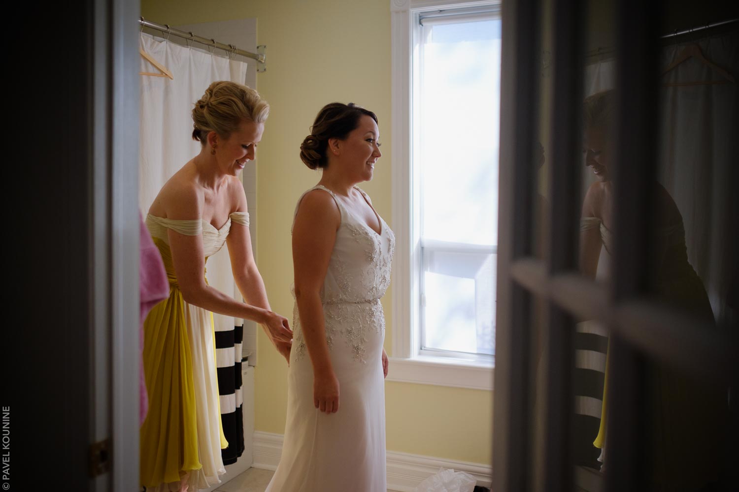 Timeless wedding photography of bride with maid of honour helping with the wedding dress.